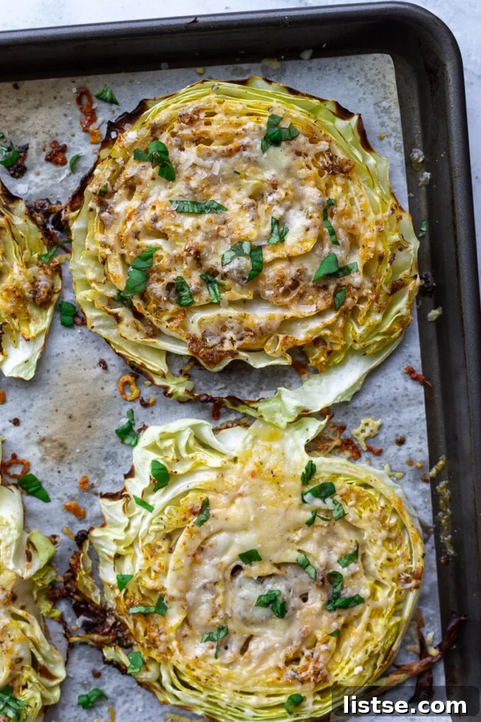 Roasted cabbage steaks covered in melted cheese and fresh basil ribbons sitting on a baking sheet