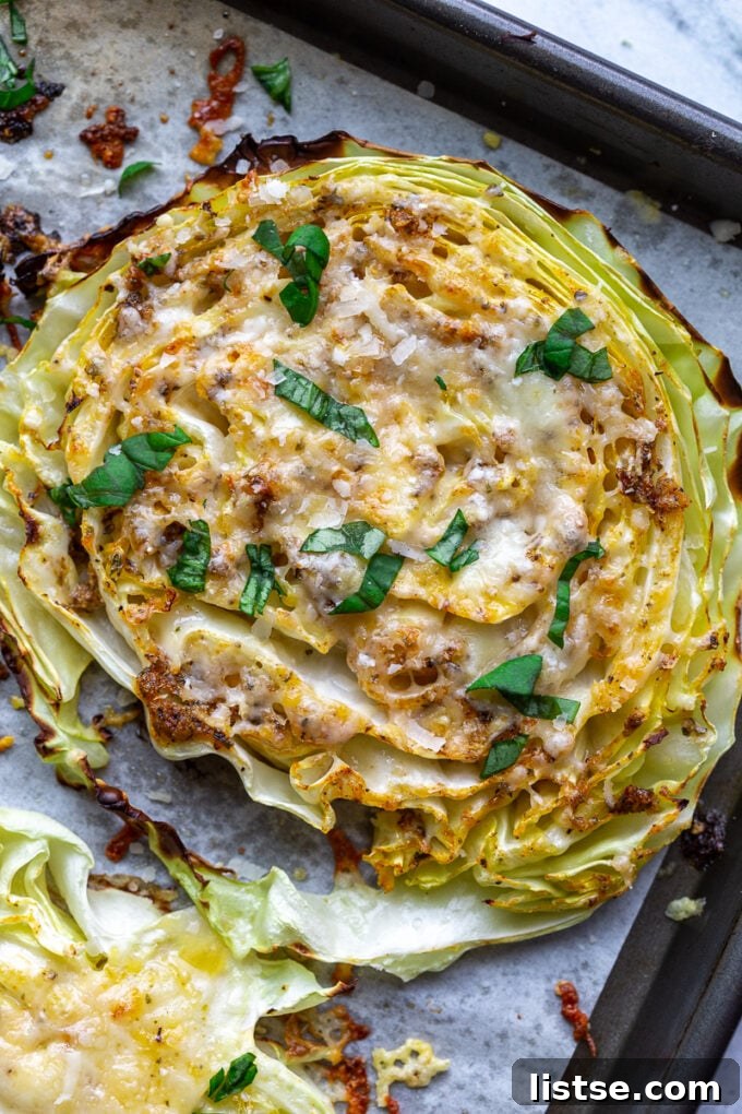 close up of Roasted cabbage steaks covered in melted cheese and fresh basil ribbons sitting on a baking sheet