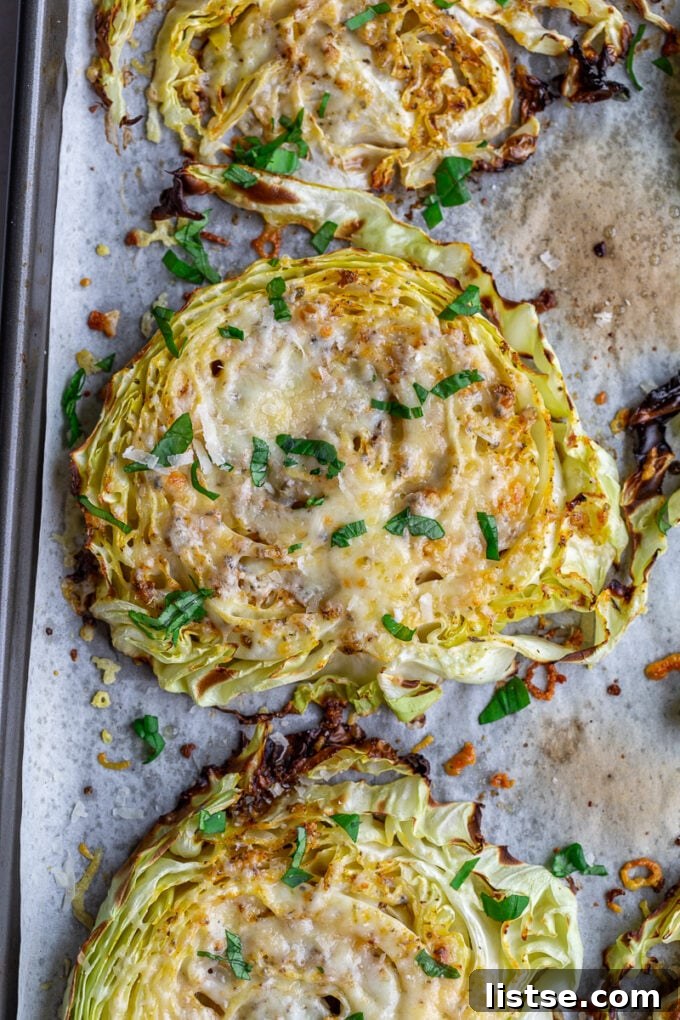 Roasted cabbage steaks covered in melted cheese and fresh basil ribbons sitting on a baking sheet