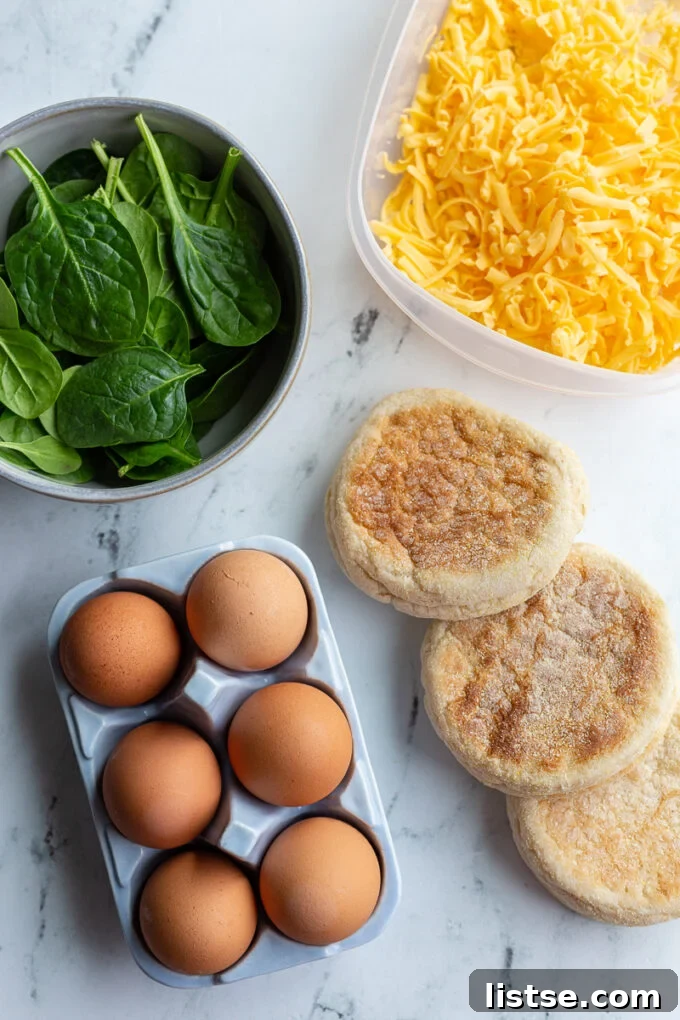 English Muffin Morning Stack 3 Ingredients for an English muffin breakfast sandwich: raw spinach, shredded cheddar cheese, brown eggs, and English muffins