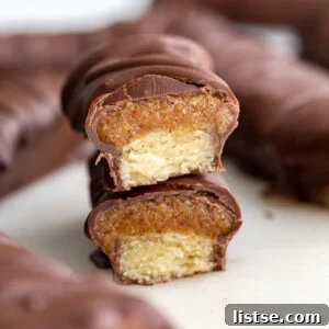 Chocolate Caramel Shortbread Bars 6 A perfectly portioned homemade Twix bar, showcasing its three distinct layers: a crunchy shortbread base, a luscious caramel-like center, and a rich chocolate coating.