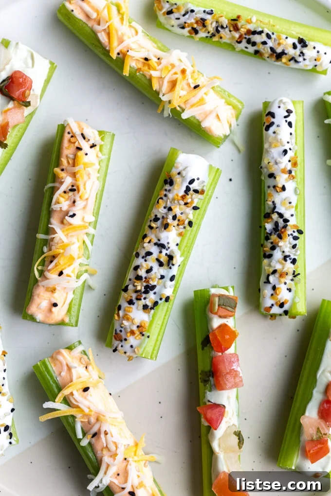 Creamy Cottage Cheese Celery Boats 2 Celery sticks on a white plate featuring three distinct whipped cottage cheese flavors: creamy buffalo with a sprinkle of shredded cheese, classic Everything Bagel seasoning, and vibrant avocado topped with fresh pico de gallo.