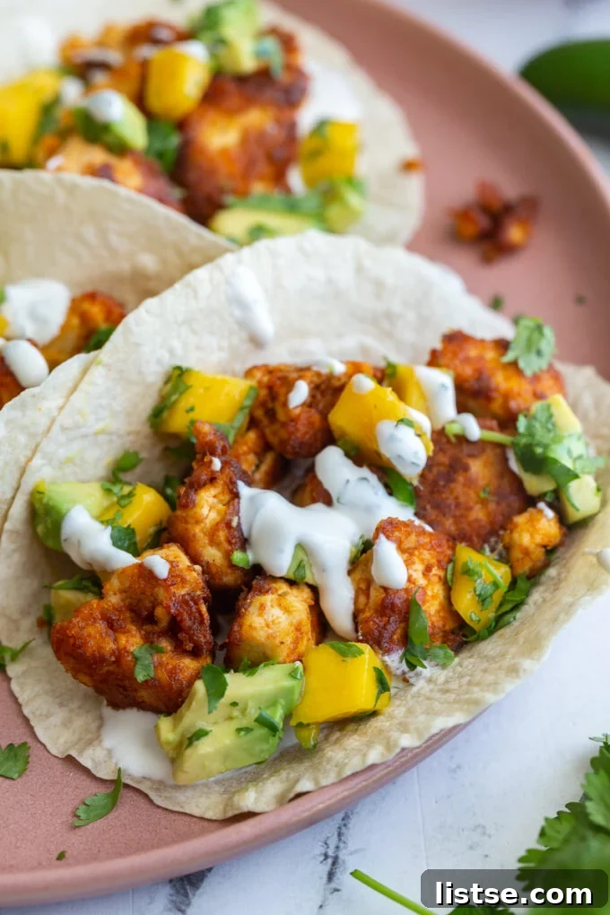 Beautifully arranged Chipotle Tofu Tacos on a pink plate, garnished with fresh mango salsa and cilantro.