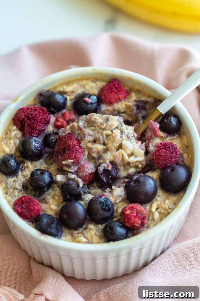 single serve baked protein oats in a ramekin and topped with fruit. A bite has been taken out of the center