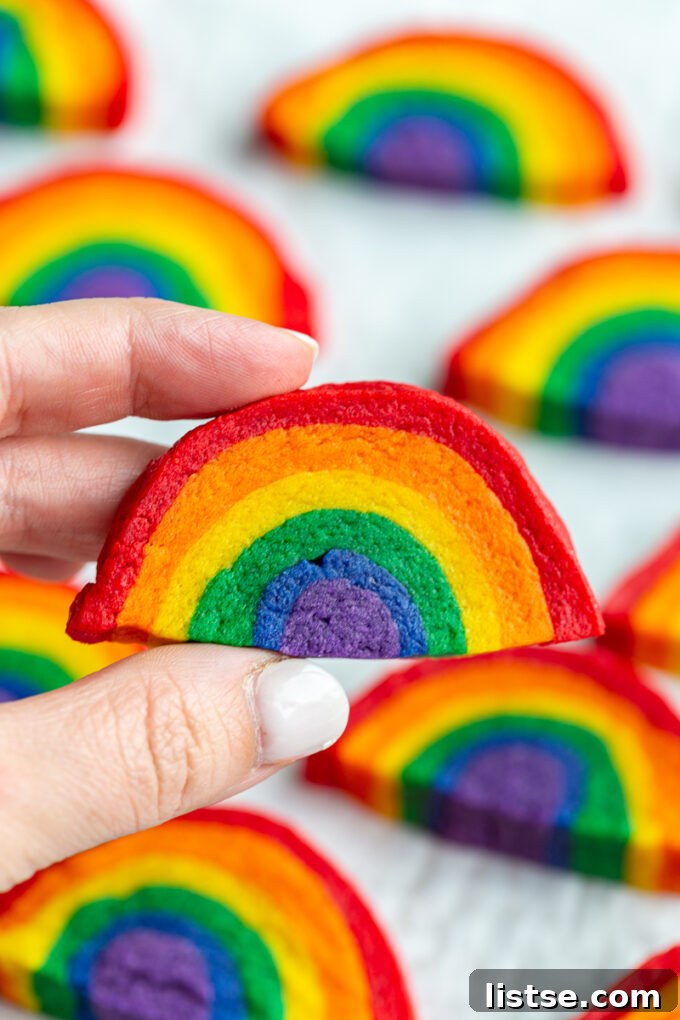 Kaleidoscope Cookies 3 A hand reaching for a colorful rainbow cookie, with more cookies in the soft focus background.
