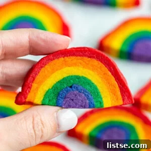 hand holding up a rainbow sugar cookie with more cookies in the background