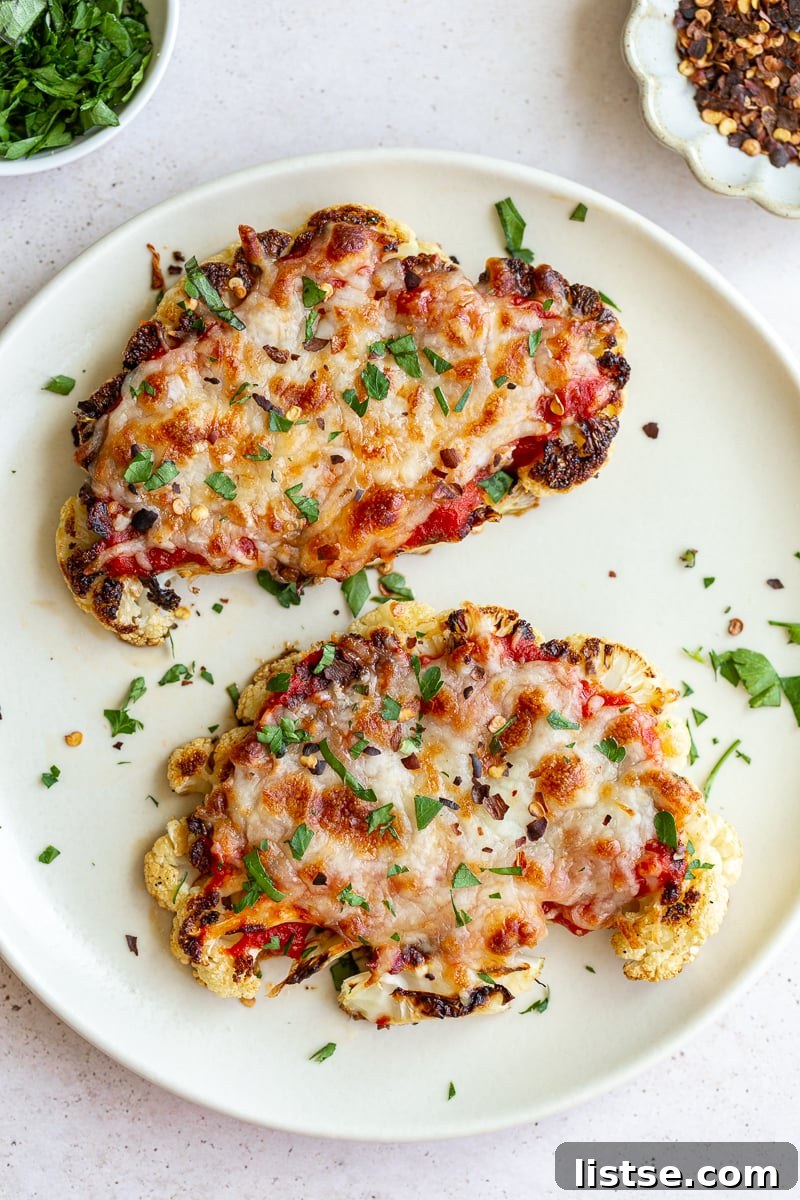 Golden Baked Cauliflower Parmesan 3 Two slices of cauliflower parmesan on a white plate, garnished with fresh basil.