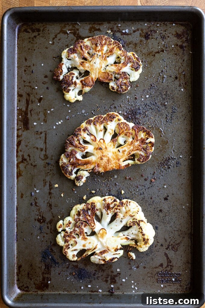 Golden Baked Cauliflower Parmesan 4 Roasted slices of cauliflower on a sheet pan, seasoned and ready for sauce.