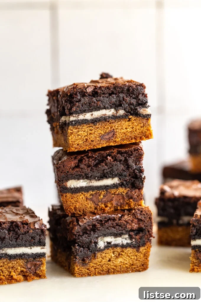 Decadent Layered Brownies 2 A decadent stack of layered Slutty Brownies showing the cookie base, Oreo layer, and fudgy brownie top, sprinkled with sea salt.