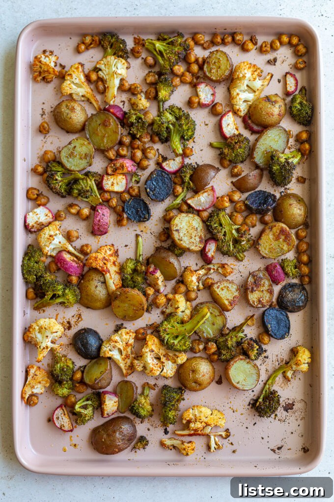 Another view of the baking tray filled with fresh, unroasted vegetables, showcasing the crispness of the broccoli and cauliflower, alongside the sturdy potatoes and radishes, hinting at the delicious transformation to come.