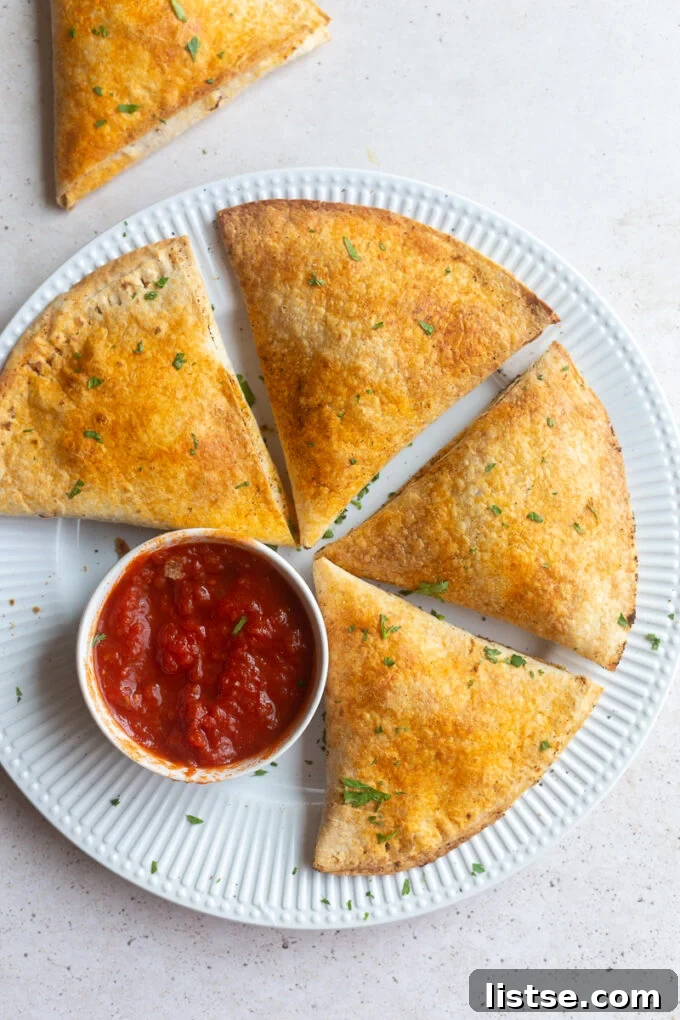 Crispy large pizza pockets made from tortillas, artfully arranged on a plate with a side cup of rich marinara dipping sauce, ready to be enjoyed.
