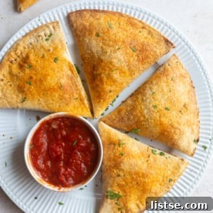 Crispy large pizza pockets made from tortillas, artfully arranged on a plate with a side cup of rich marinara dipping sauce.