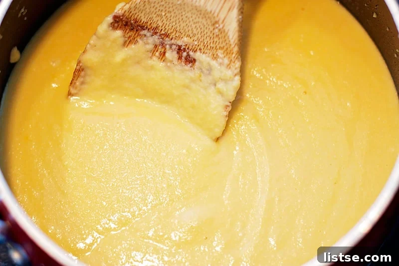 Melted cheese being stirred into the roux to create a rich, smooth sauce for the mac and cheese.