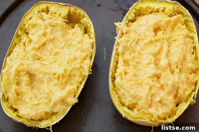 Twice Baked Spaghetti Squash Mac n' Cheese, with the cheesy squash mixture piled back into the squash shells, ready for final baking.