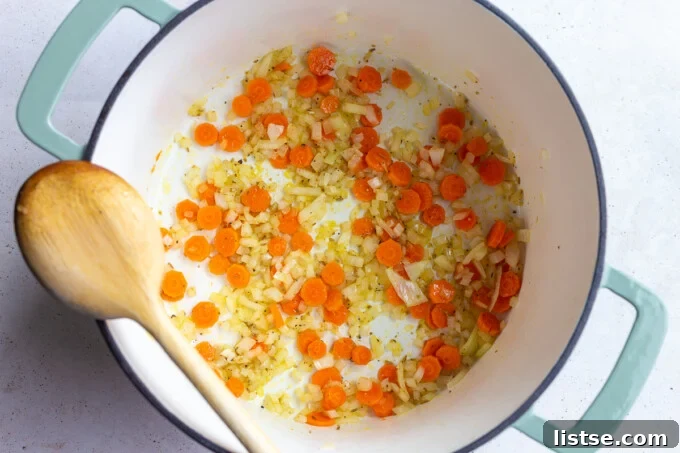 Diced onions and carrots sautéing in a large pot with olive oil.