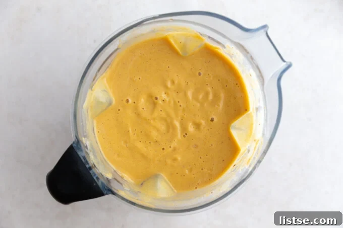 Golden Roasted Cauliflower Velouté 5 A blender filled with the vibrant orange roasted cauliflower soup, freshly blended to a creamy consistency