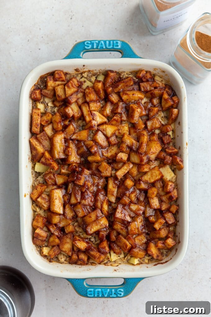 Apple Crumble Baked Oatmeal 2 baked oatmeal topped with cinnamon apple chunks in a small teal baking dish, ready to be enjoyed