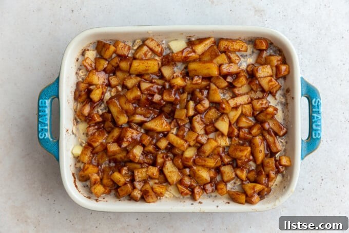 Apple Crumble Baked Oatmeal 6 baked oatmeal topped with cinnamon apple chunks in a small teal baking dish, showcasing the golden-brown apples