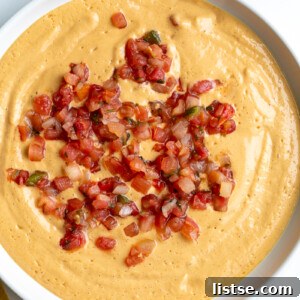 tofu queso cheese dip in a large bowl topped with pico de gallo