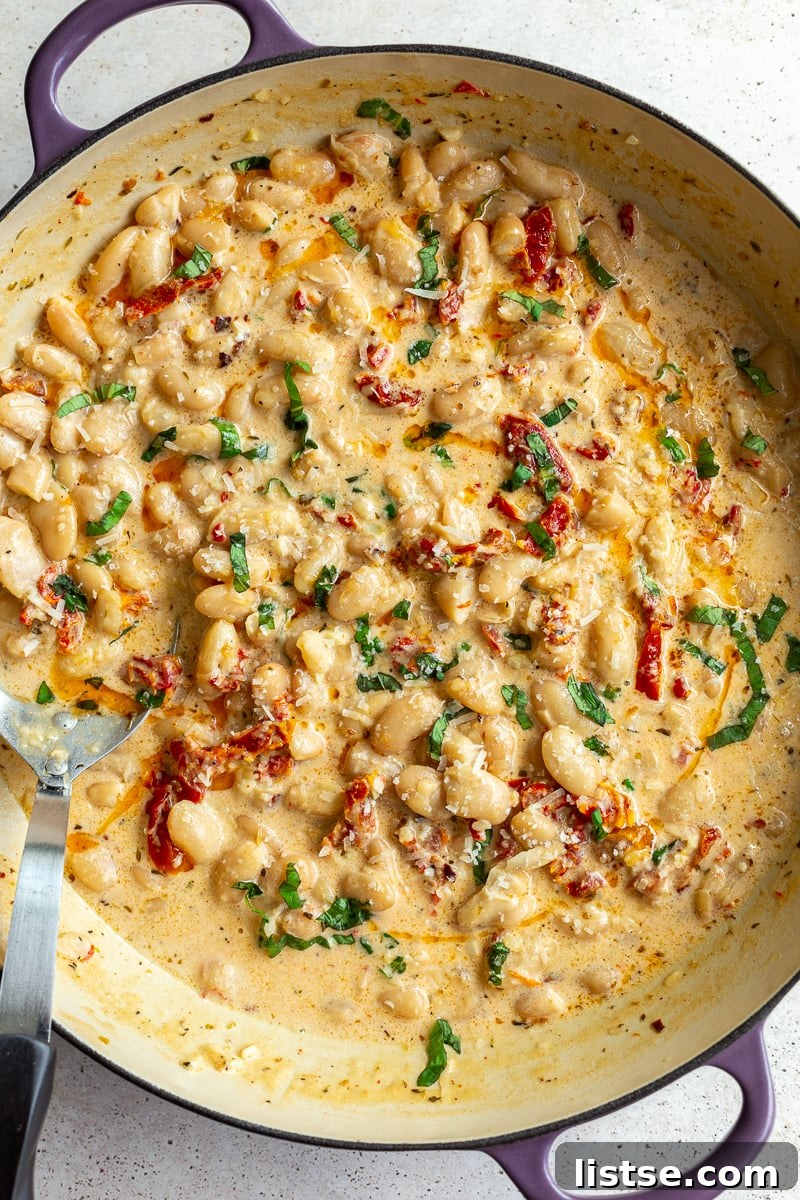 Large skillet brimming with creamy butter beans and vibrant sundried tomatoes, adorned with fresh basil. A classic 'Marry Me Butter Beans' presentation.