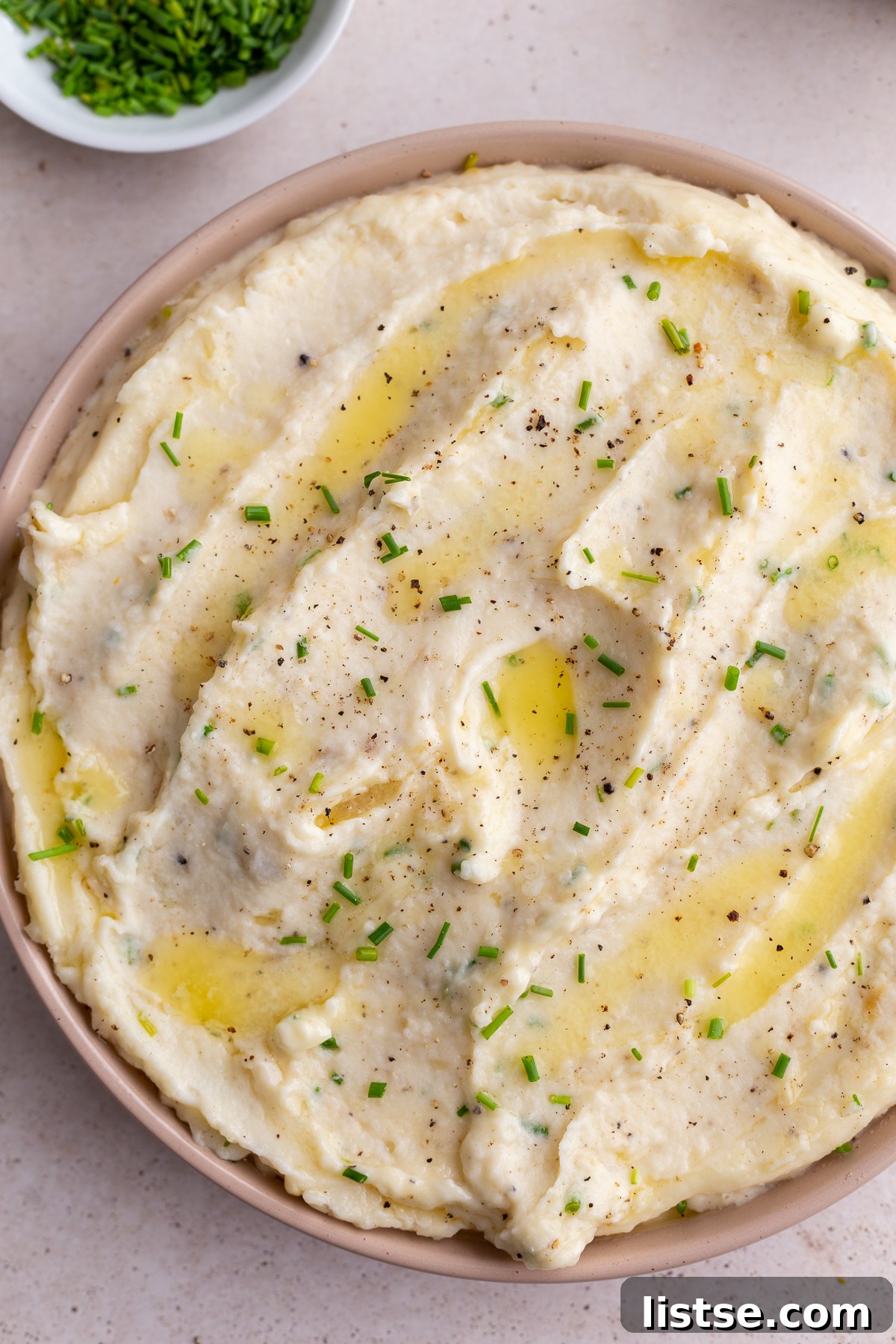 Golden Roasted Garlic Mash 3 Large pink bowl overflowing with rich, creamy roasted garlic mashed potatoes, generously topped with vibrant diced chives.