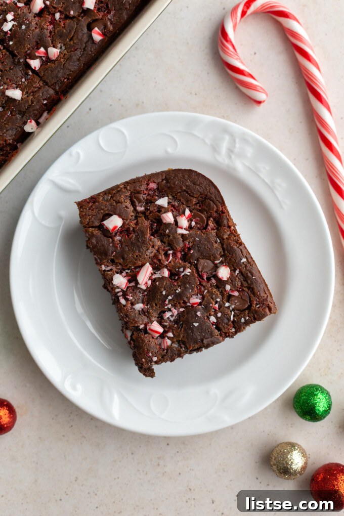 Decadent Mint Chocolate Baked Oats 4 A slice of chocolate peppermint baked oats on a white plate, showcasing the fluffy texture and the festive crushed peppermint topping.