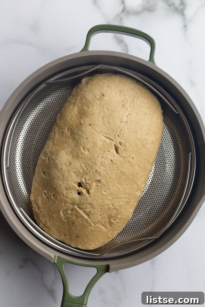 Stuffed Vegan Holiday Roast 8 The seitan loaf, now fully shaped and sealed, placed inside a steamer basket, ready for the crucial steaming process to develop its tender texture.