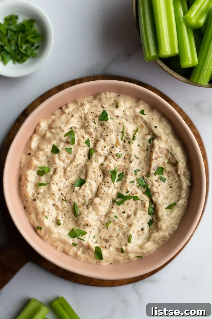 A vibrant bowl of High-Protein French Onion Dip ready to be enjoyed with fresh Dandy celery sticks on a rustic background.