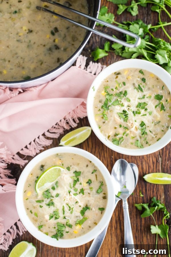 A rich and creamy bowl of White Chicken Chili, garnished with vibrant fresh cilantro and a lime wedge.