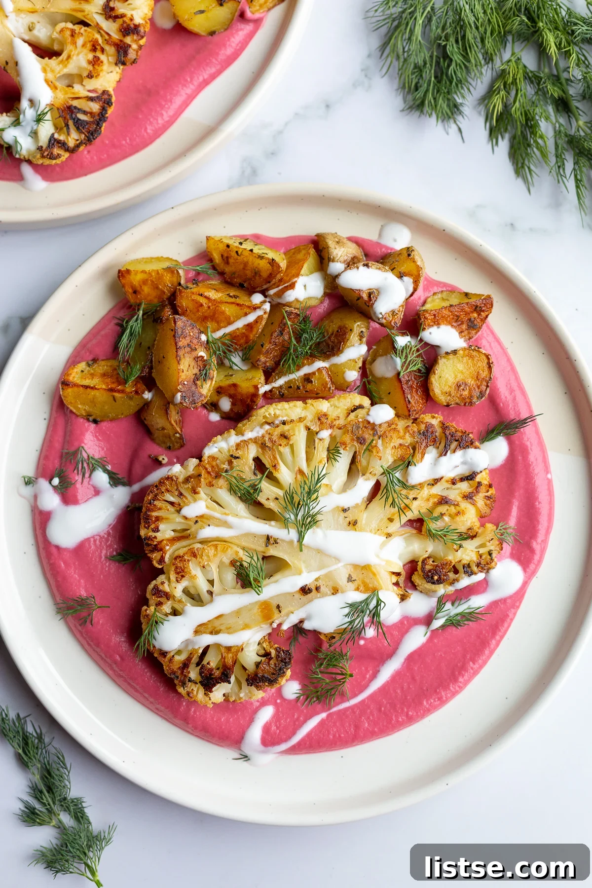 Seared Cauliflower Steaks with Vibrant Beet & Bean Puree 3 roasted cauliflower steak and roasted baby potatoes on a bed of beet been puree and drizzled with yogurt
