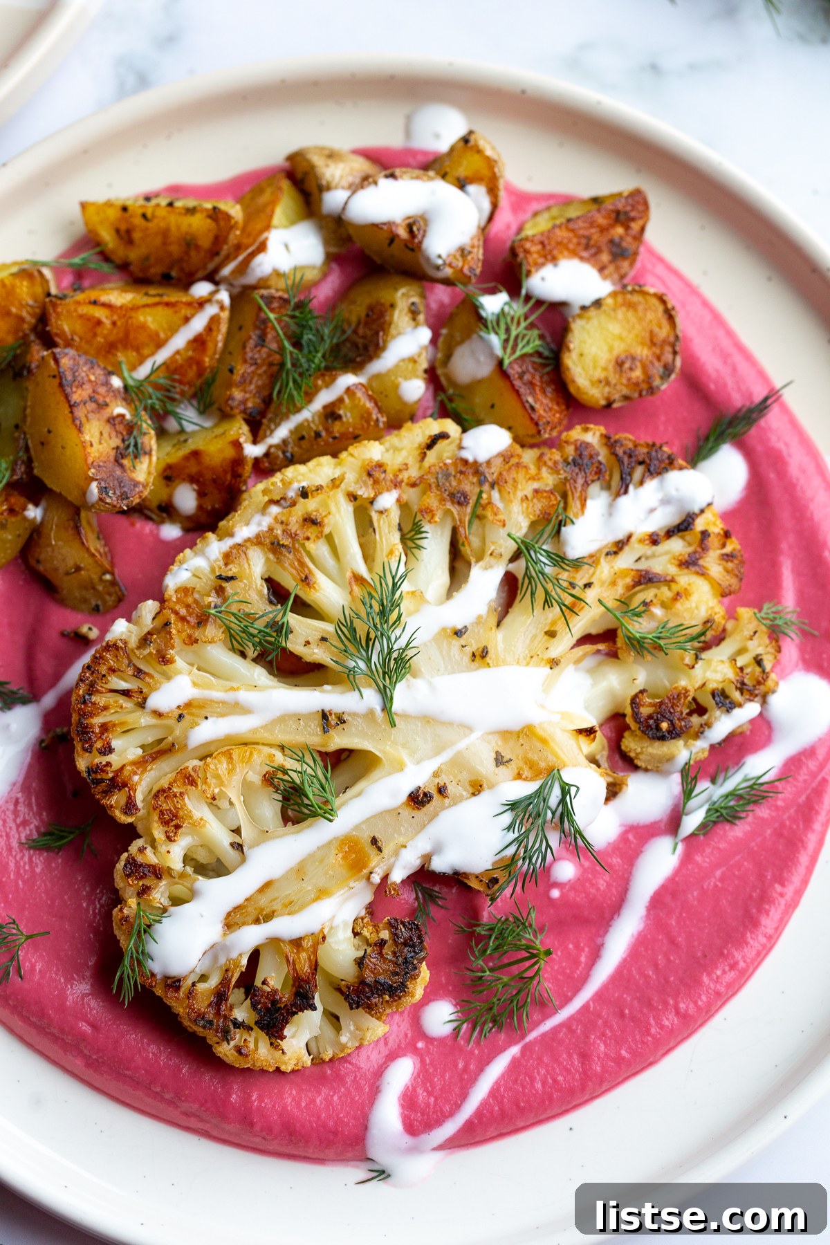 Seared Cauliflower Steaks with Vibrant Beet & Bean Puree 7 Finished dish of roasted cauliflower steaks and potatoes with beet puree and yogurt drizzle.