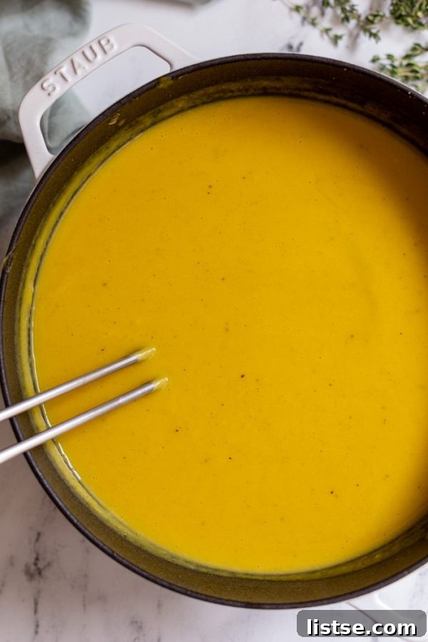 creamy butternut squash soup simmering in a vibrant orange dutch oven