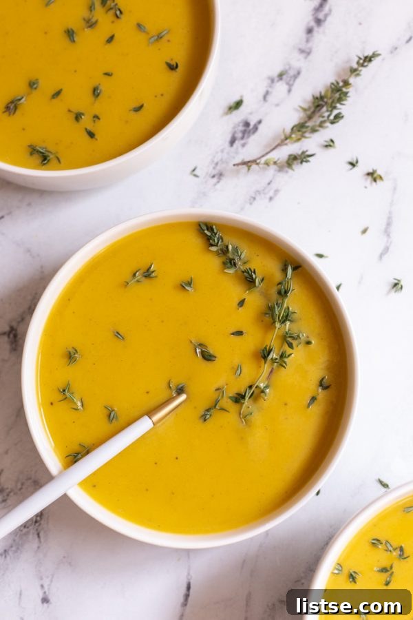 three bowls of vegan butternut squash soup garnished with fresh herbs and a drizzle of cream