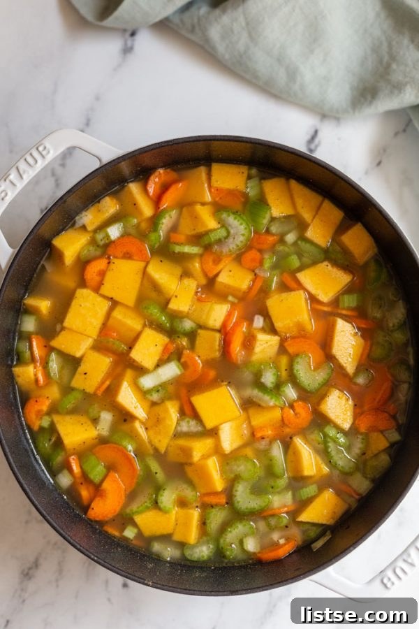 unblended vegan butternut squash soup with chunky vegetables simmering in a dutch oven