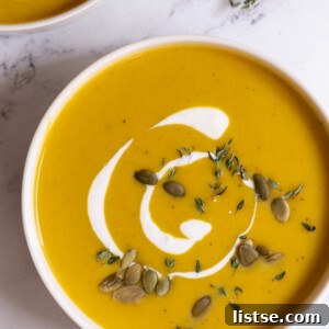 bowls filled with creamy butternut squash soup and topped with cream and pepitas