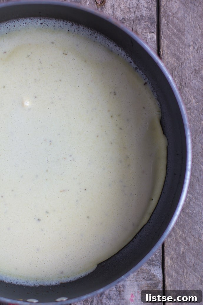 Crepe batter being swirled in a hot skillet for a thin layer