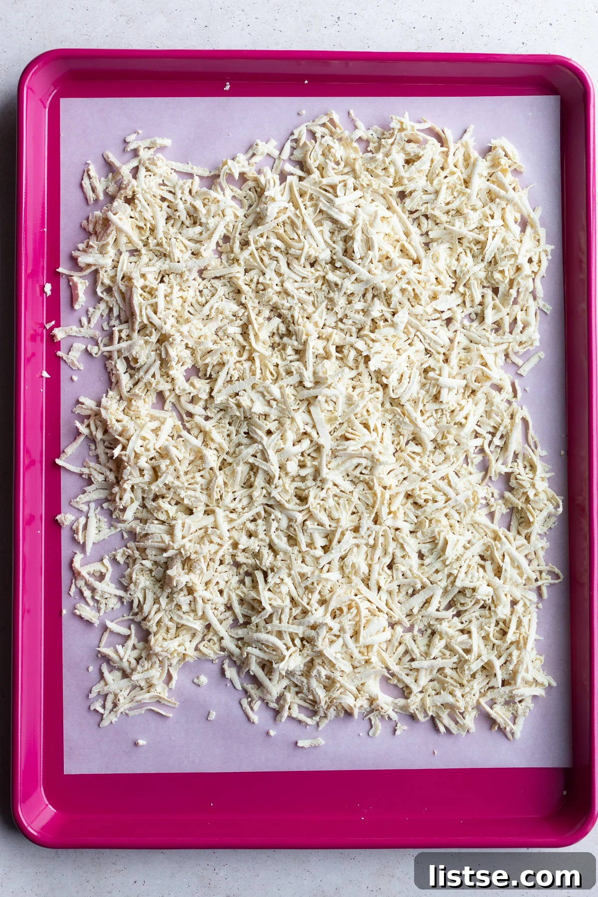 Shredded firm tofu evenly spread on a baking sheet for crispy texture