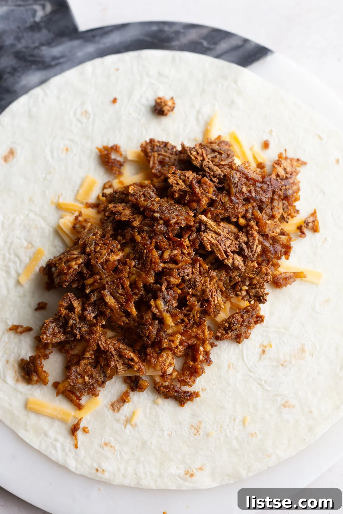 Assembled high protein vegan burrito showcasing the shredded tofu, queso, and fresh toppings
