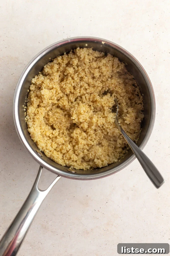 Fluffy, cooked quinoa resting in a small pan, ready to be served as the base for the veggie bowls