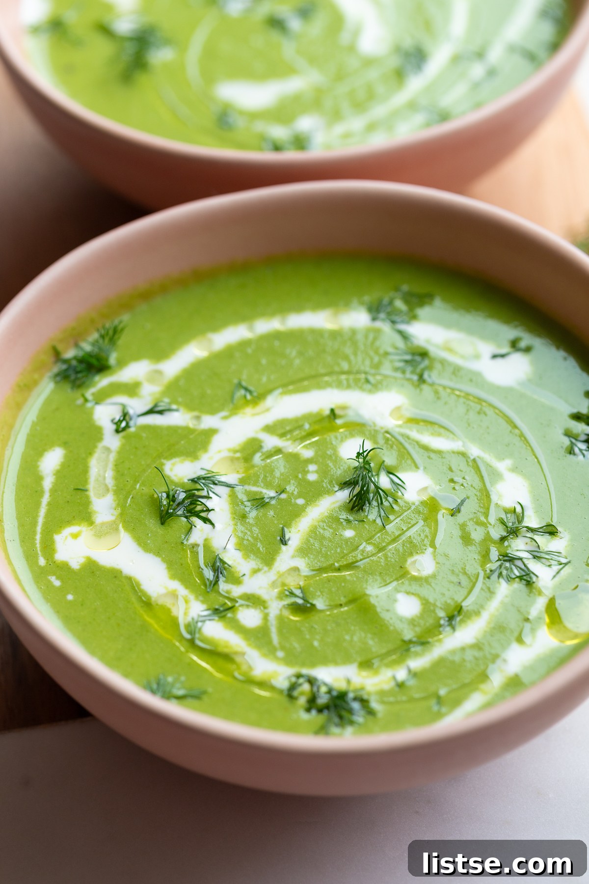 Green Goddess Soup in a pink bowl with an elegant cream drizzle, ready to be served.