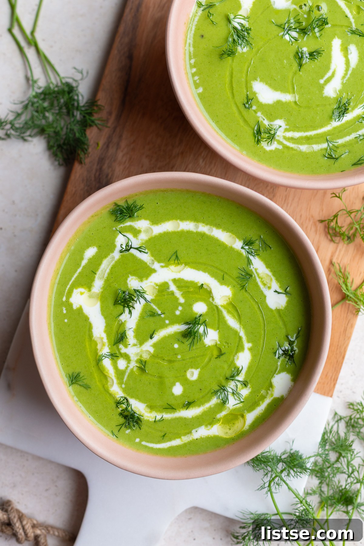A close-up shot of the creamy, vibrant green Green Goddess Soup in a pink bowl, highlighting its inviting texture.