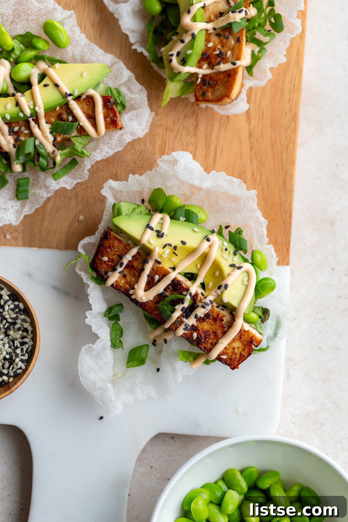Crispy Tofu Rice Paper Tacos 2 Crispy rice paper tacos topped with fresh lettuce, creamy avocado, and savory tofu slices, drizzled with spicy mayo.