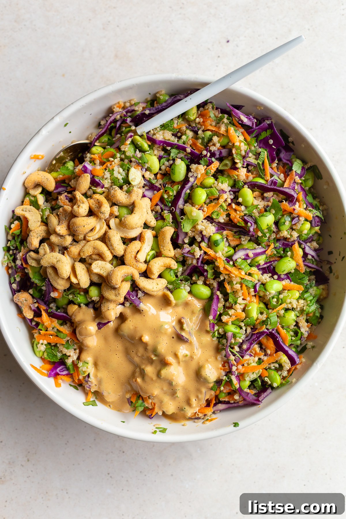 Stirring the dressing and cashews into the salad.