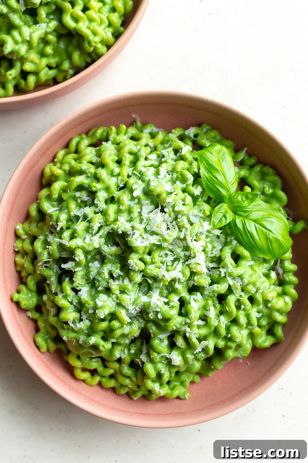 Emerald Goddess Pasta Delight 2 A beautifully plated bowl of Green Goddess Pasta, featuring vibrant green sauce coating short pasta, garnished with fresh herbs, in a delicate pink ceramic bowl, ready to be enjoyed.