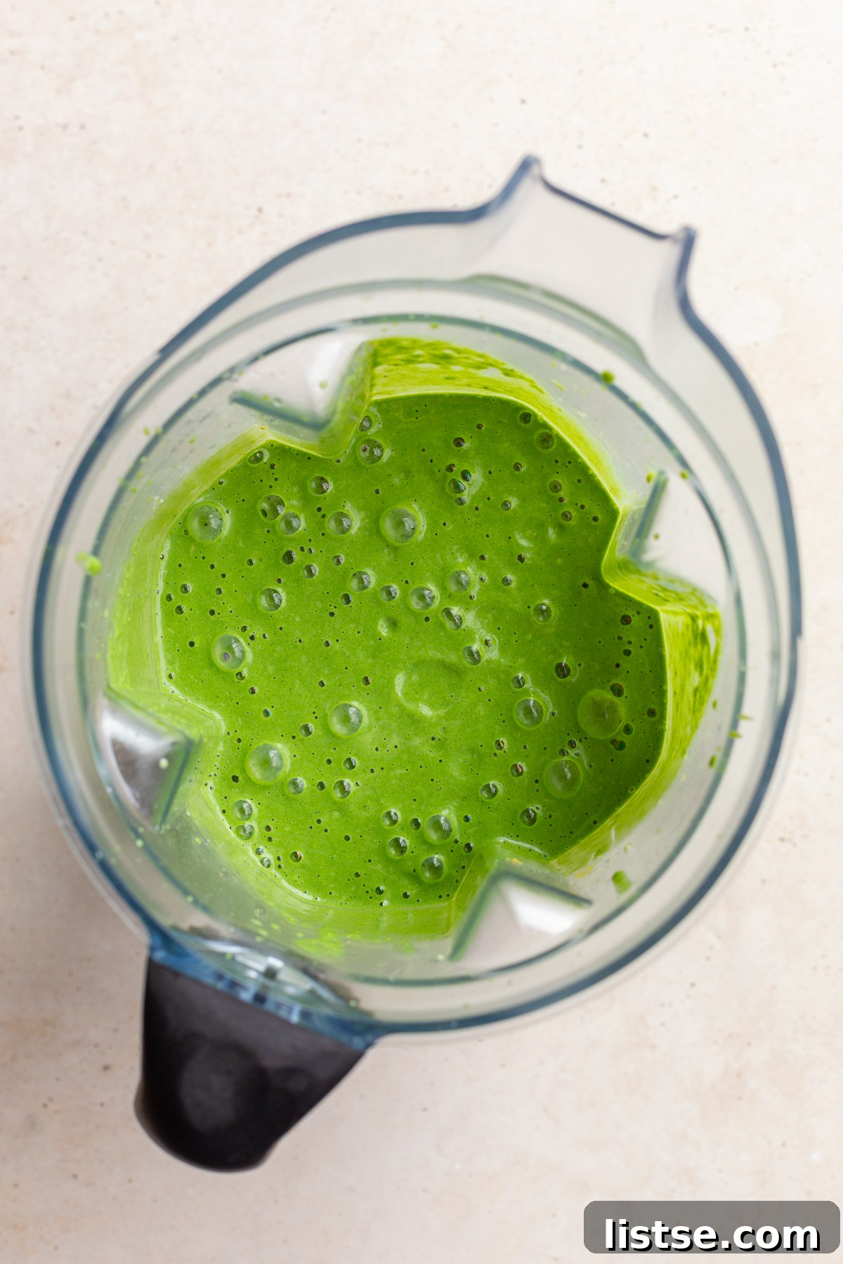 Emerald Goddess Pasta Delight 3 A high-angle shot of a vibrant green pasta sauce being blended in a modern high-speed blender, showcasing the smooth, creamy texture of the fresh herb and spinach mixture.