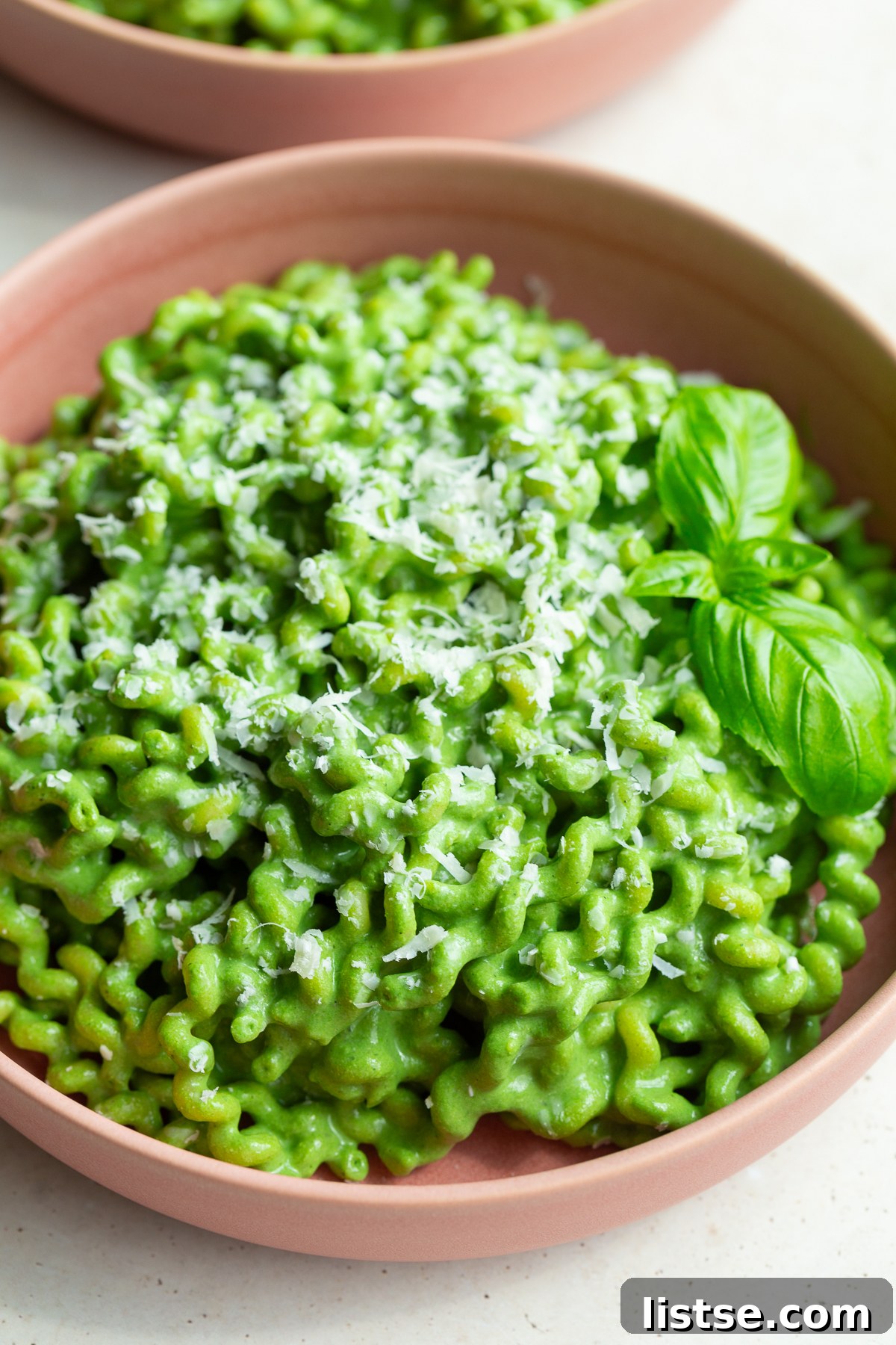 Emerald Goddess Pasta Delight 5 A close-up view of Green Goddess Pasta, featuring fusilli noodles perfectly tossed in a rich, creamy, vibrant green sauce, served in an inviting pink bowl.
