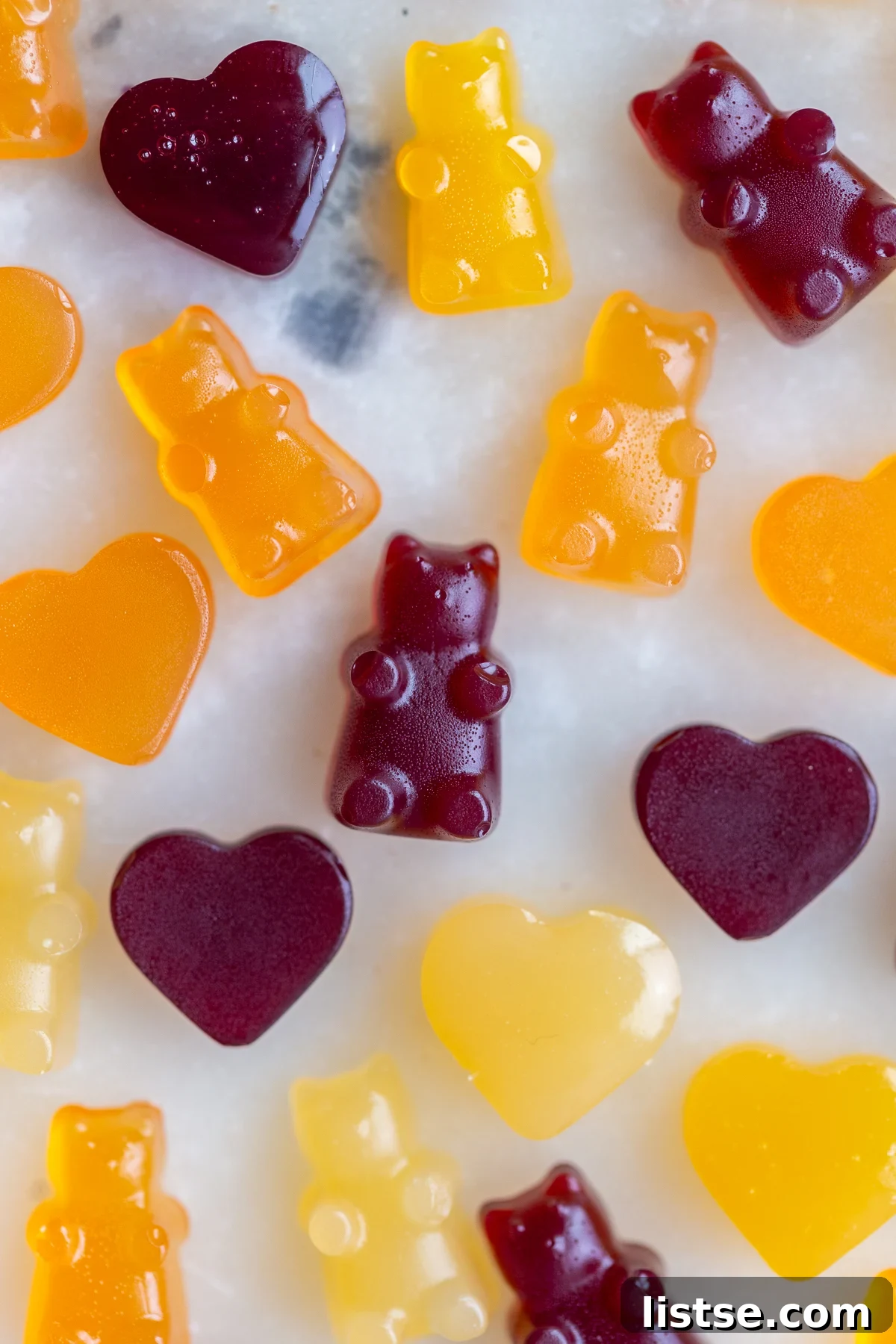 A vibrant selection of homemade vegan gummy bears in cheerful orange, sunny yellow, and deep red, artfully arranged to showcase their natural colors and uniform shapes.