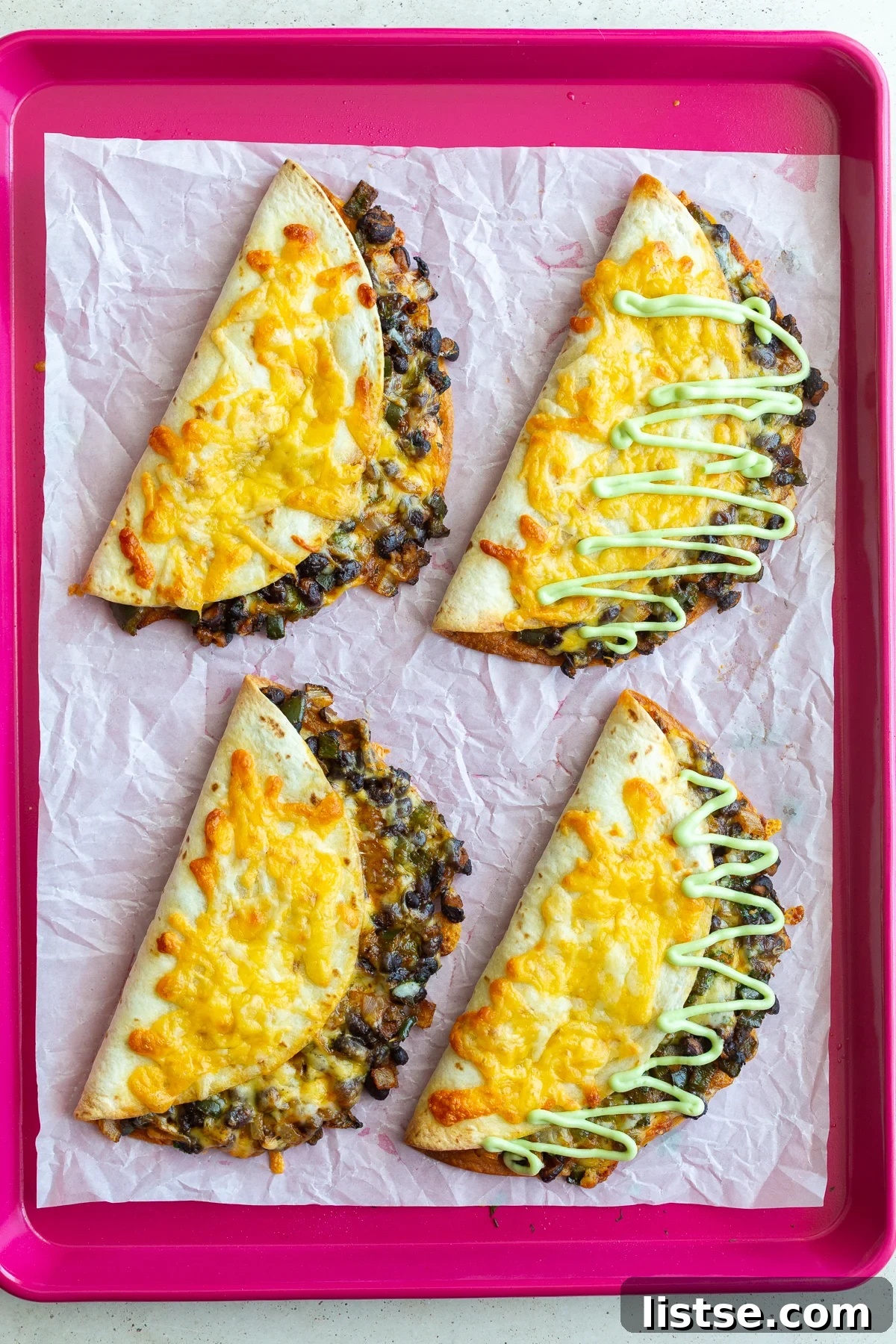 Cheesy black bean tacos neatly arranged on a vibrant red baking sheet, ready for serving.