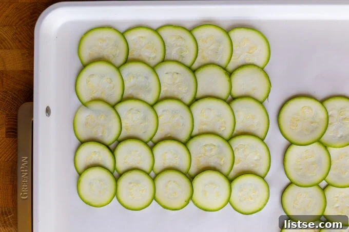 Skinny Zucchini Roll-Ups 4 Thinly sliced zucchini rounds arranged on parchment paper.
