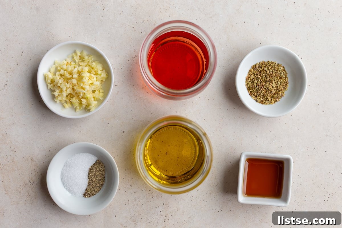 Close-up of the homemade Mediterranean salad dressing ingredients: olive oil, red wine vinegar, minced garlic, dried oregano, honey or maple syrup, salt, and black pepper.